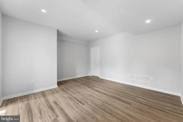 a view of an empty room with wooden floor and closet
