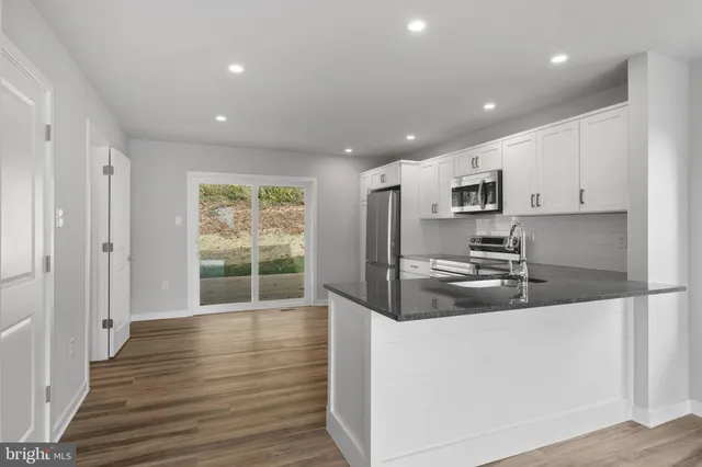 a kitchen with kitchen island granite countertop a sink cabinets and stainless steel appliances