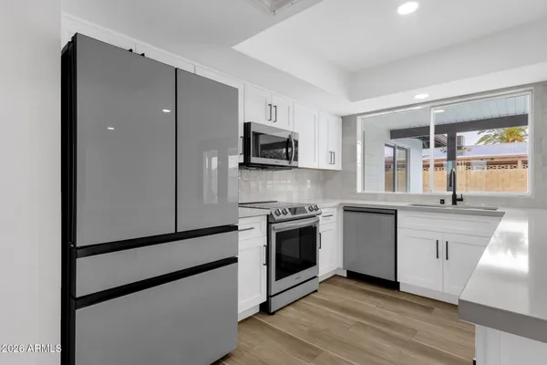 a kitchen with granite countertop a refrigerator and wooden floor