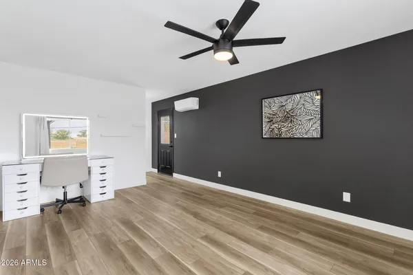 a view of empty room with wooden floor and fan