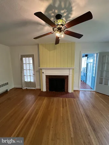 a view of an empty room with wooden floor and a fireplace