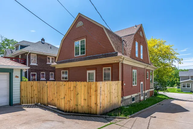 a view of a blue house with large windows and a small yard