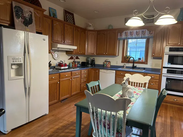 a kitchen with stainless steel appliances granite countertop a dining table chairs refrigerator and sink