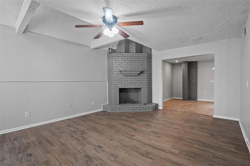 2156 Fleur De Lis Court Arlington, TX 76012 - Photo 2 of 16 an empty room with wooden floor a ceiling fan a fireplace and entryway