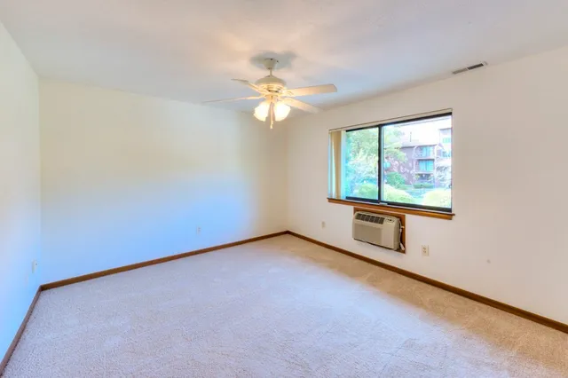 an empty room with windows and fan