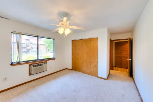 an empty room with windows cabinet and chandelier fan