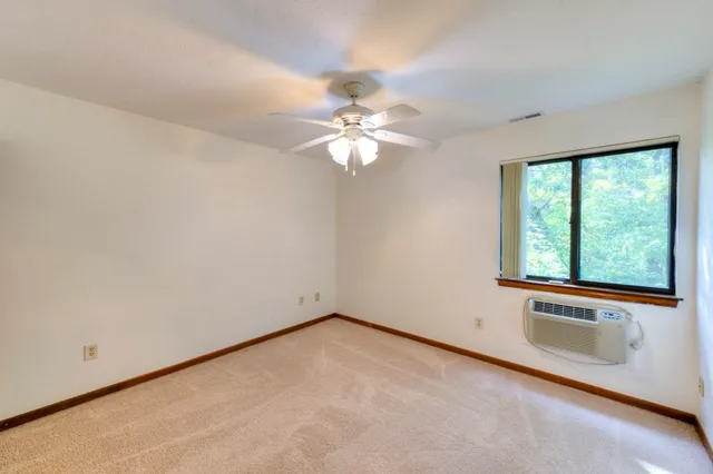 an empty room with windows and fan