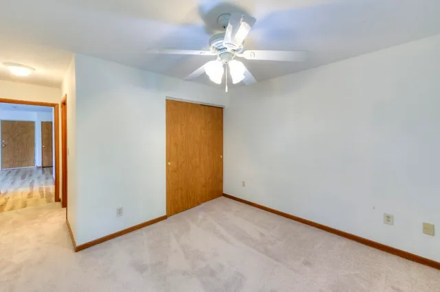 an empty room with a chandelier fan and windows