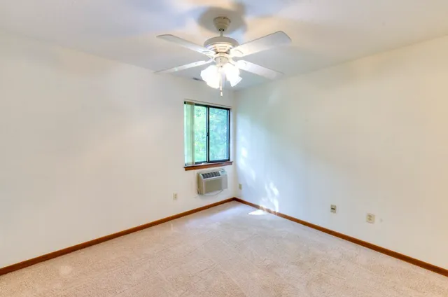 an empty room with a window and a fan