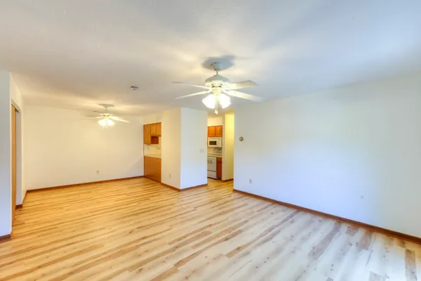 a view of a room with wooden floor and a ceiling fan