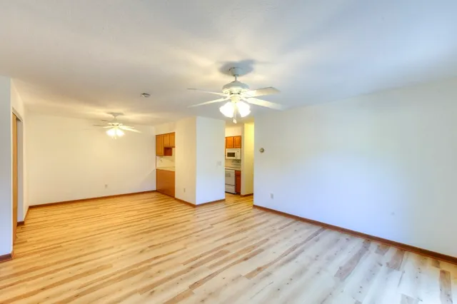 a view of a room with wooden floor and a ceiling fan