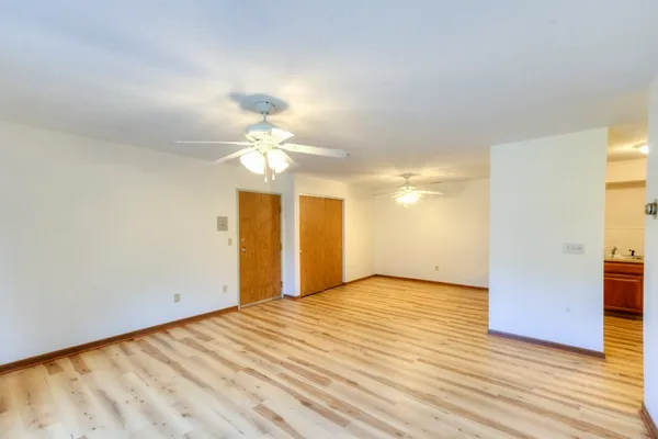 a view of a big room with wooden floor a chandelier fan and windows