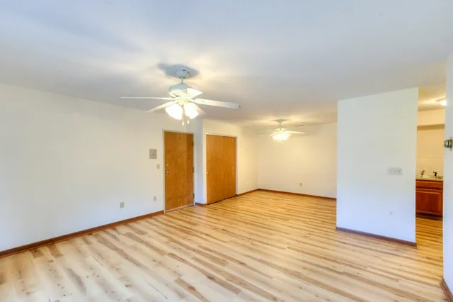 a view of a big room with wooden floor a chandelier fan and windows