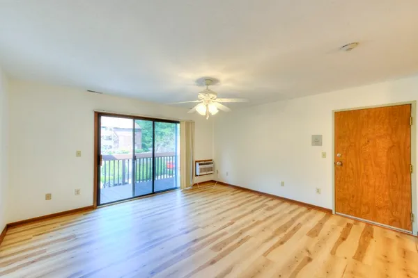 an empty room with wooden floor fan and windows