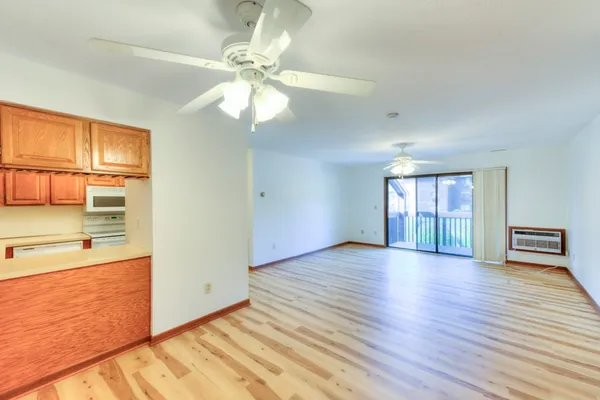 a view of an empty room with window and wooden floor
