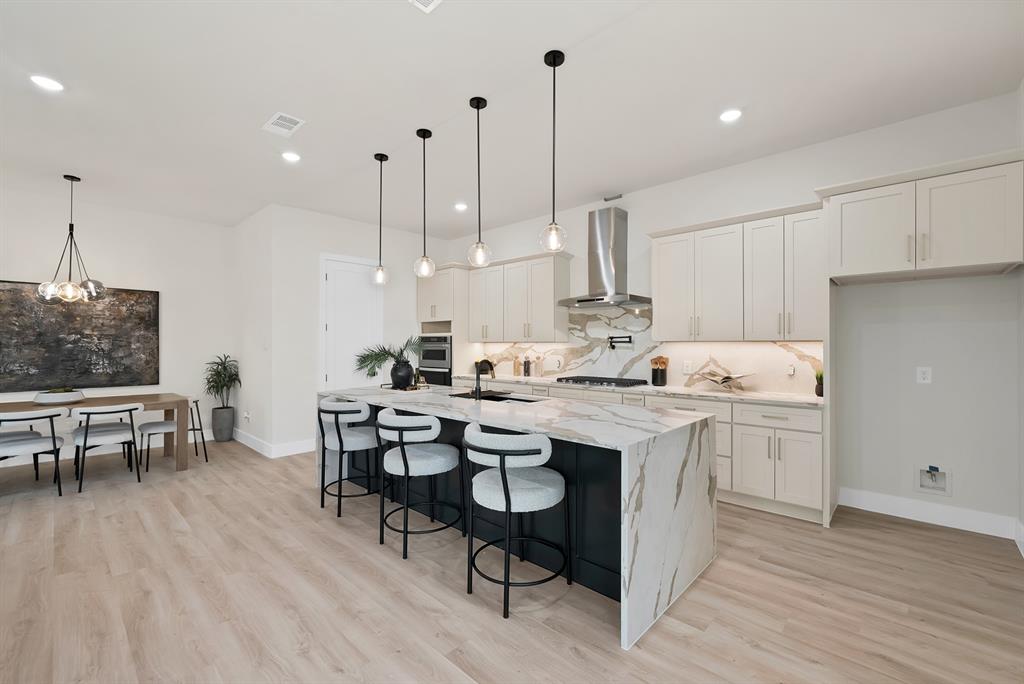 1415 Fayette Street Dallas, TX 75203 - Photo 13 of 40 Kitchen with a waterfall-edge island, light-toned wood-finish flooring, built-in stainless steel oven, and a stainless steel range hood