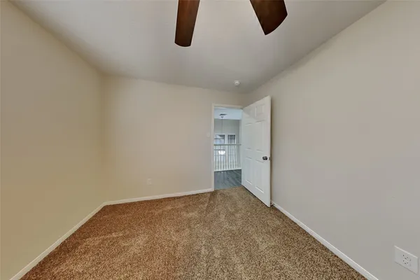 a view of an empty room with chandelier fan and a window