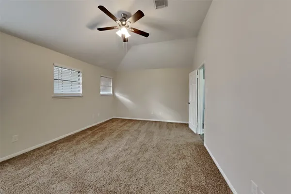 an empty room with a chandelier fan and windows