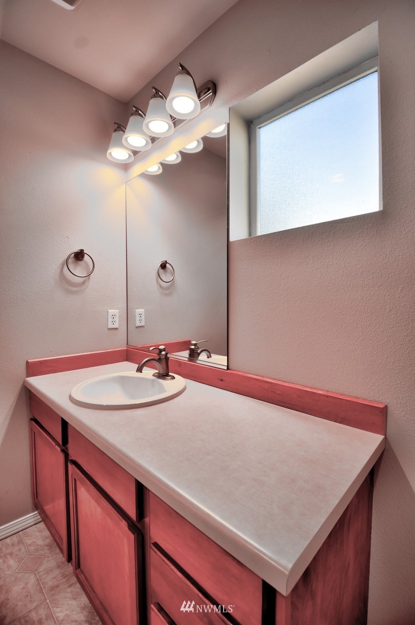 5305 Military Road East, Unit G Tacoma, WA 98446 - Photo 17 of 22 a bathroom with a sink a mirror and a light fixture