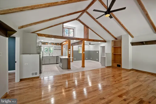 a view of an empty room with wooden floor and two window