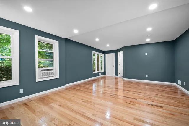 a view of an empty room with wooden floor and a ceiling fan