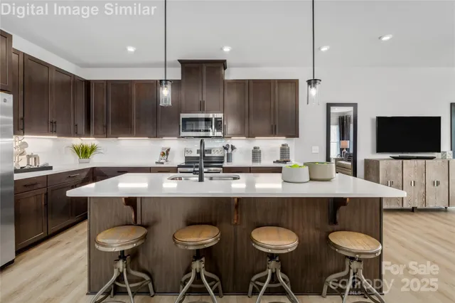 a kitchen with stainless steel appliances granite countertop a sink a stove a kitchen island and chairs with wooden floor