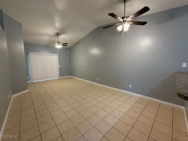 a view of an empty room and chandelier fan