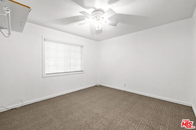 an empty room with a chandelier fan and windows