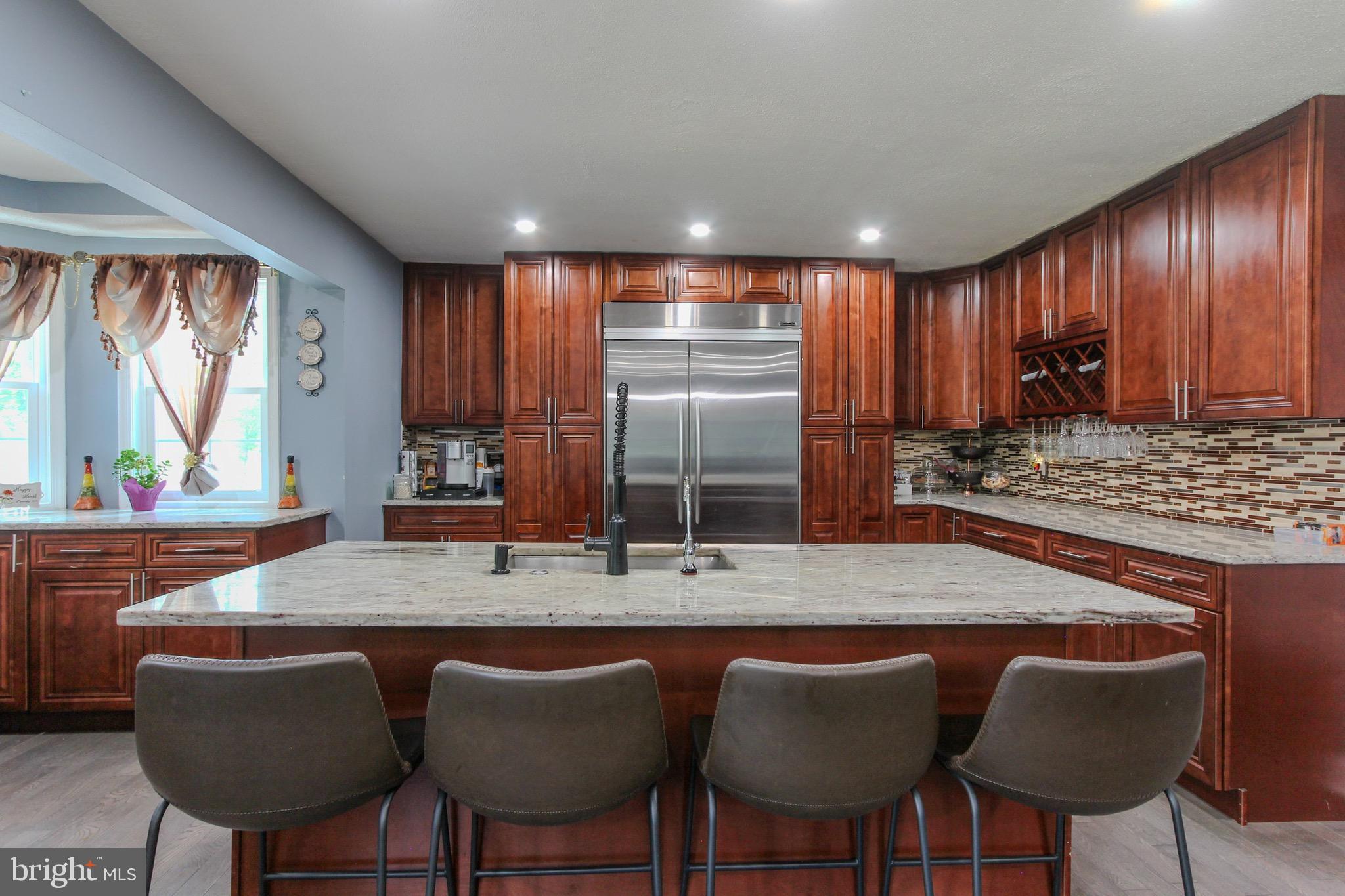 911 South Wieker Road Severn, MD 21144 - Photo 38 of 73 a kitchen with stainless steel appliances granite countertop a table chairs sink refrigerator and granite counter top