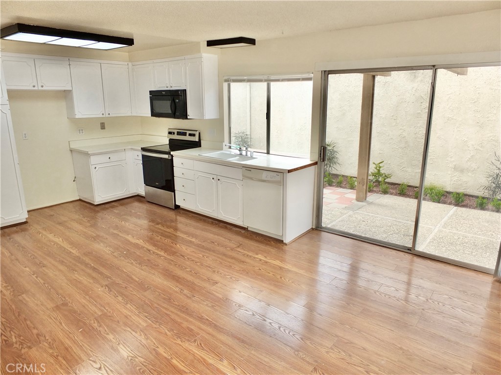 14431 Raintree Road Tustin, CA 92780 - Photo 18 of 53 a kitchen with a sink a counter top space stainless steel appliances a large window and a view of living room