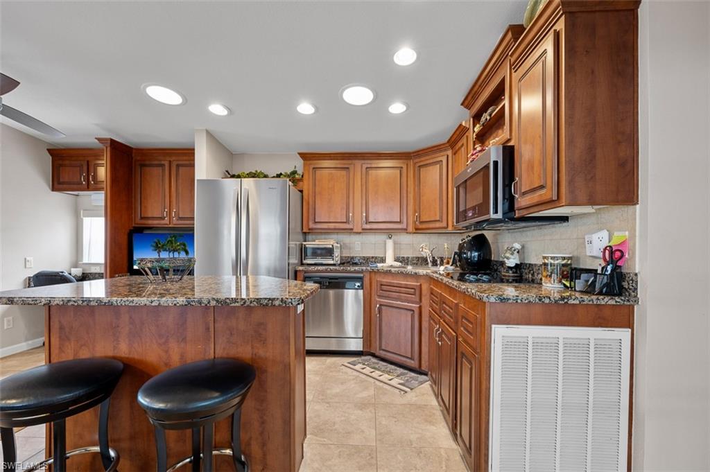 1515 Ruby Lake Point Naples, FL 34114 - Photo 13 of 21 a kitchen with stainless steel appliances granite countertop a stove a sink dishwasher a refrigerator and a microwave