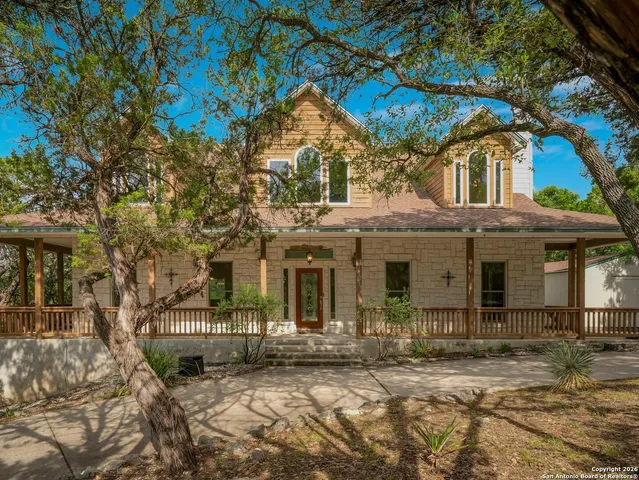 a view of a white house with large tree and wooden fence