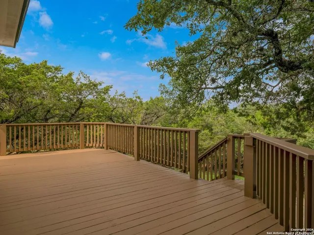 a balcony with wooden floor and trees