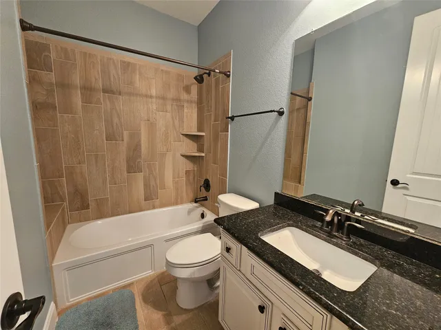 a bathroom with a granite countertop sink toilet and shower