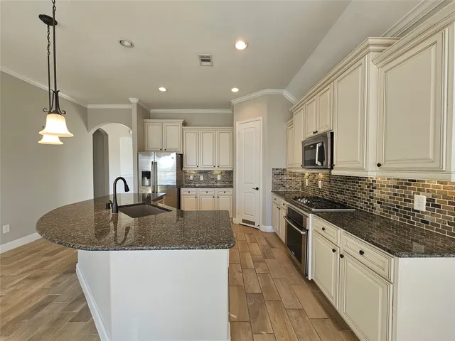 a kitchen with stainless steel appliances granite countertop a sink a stove top oven a counter space and cabinets