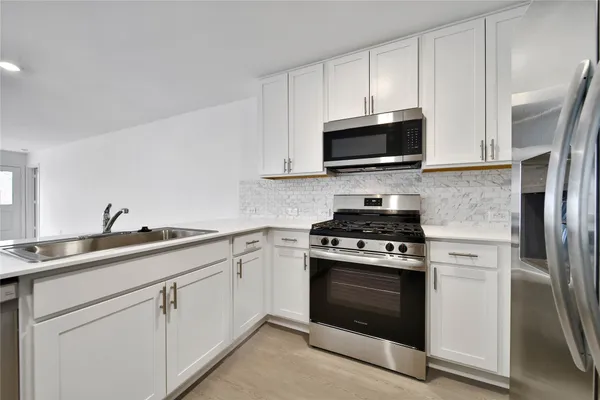 a kitchen with cabinets stainless steel appliances a sink and a stove
