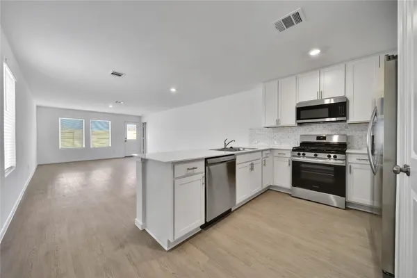 a kitchen with granite countertop a stove a sink and a refrigerator