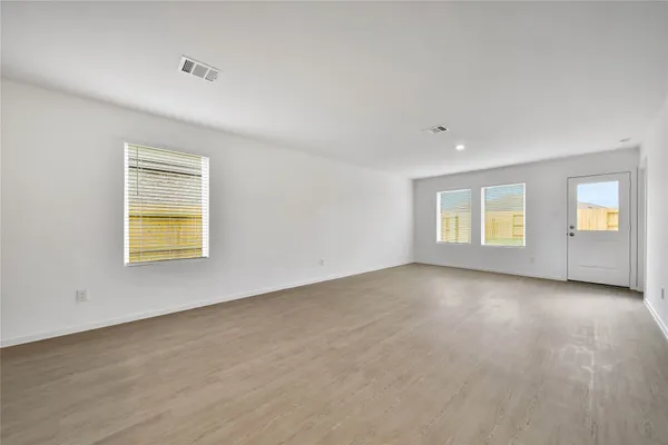 a view of an empty room with a window and wooden floor