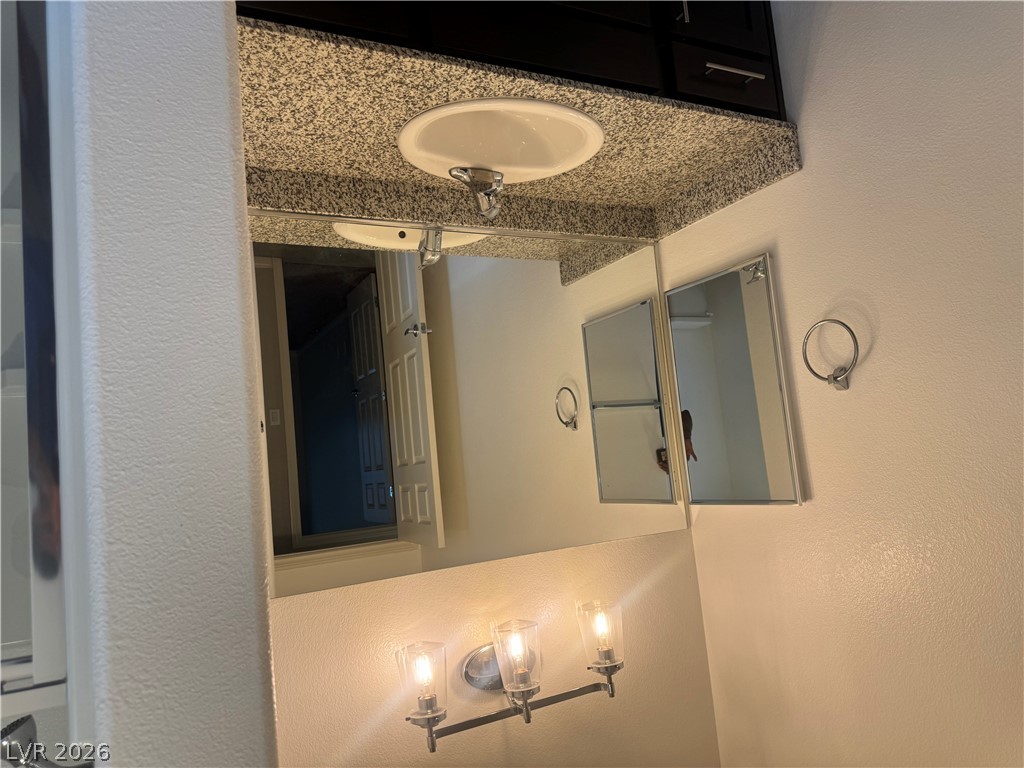 55 Canopus Ridge Way Las Vegas, NV 89183 - Photo 20 of 53 A polished granite vanity counter pairs with a large mirror in this updated bathroom.