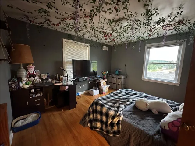 a bedroom with a bed and a flat tv screen on dresser
