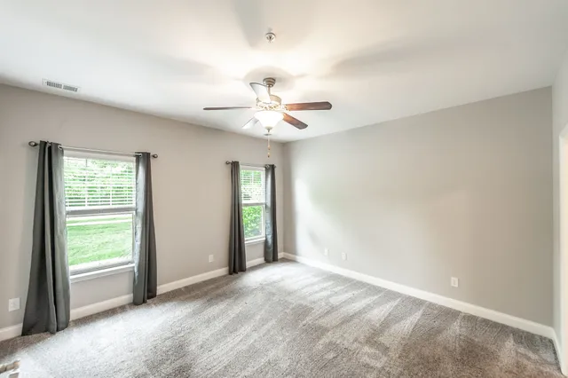 an empty room with closet and a ceiling fan