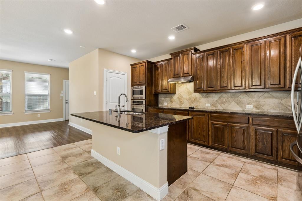 537 Hunt Farms Road Fate, TX 75189 - Photo 8 of 36 Kitchen featuring a center island with a sink, dark wood cabinetry, integrated stainless steel appliances, and tile flooring