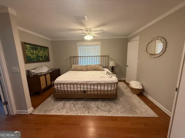a bedroom with a bed and dresser with wooden floor
