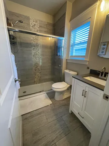 a bathroom with a granite countertop sink toilet and shower