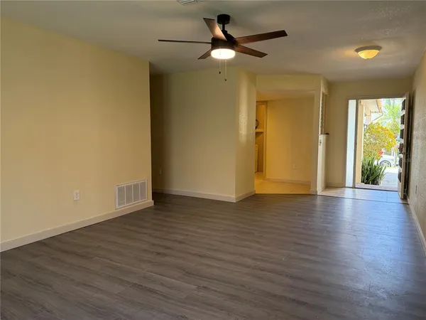 a view of an empty room with wooden floor and a window