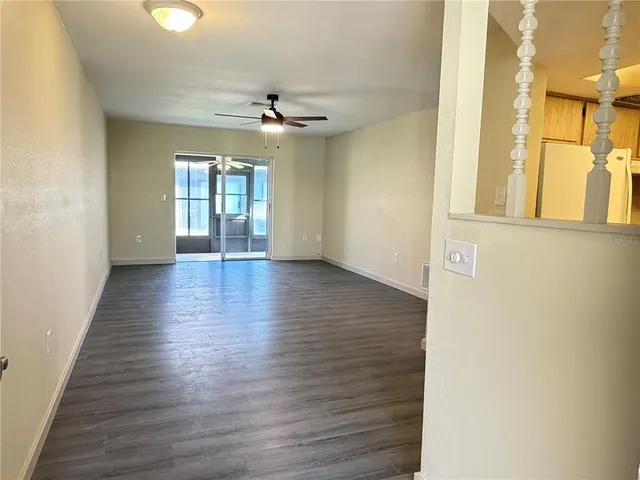 a view of an empty room with a window and wooden floor