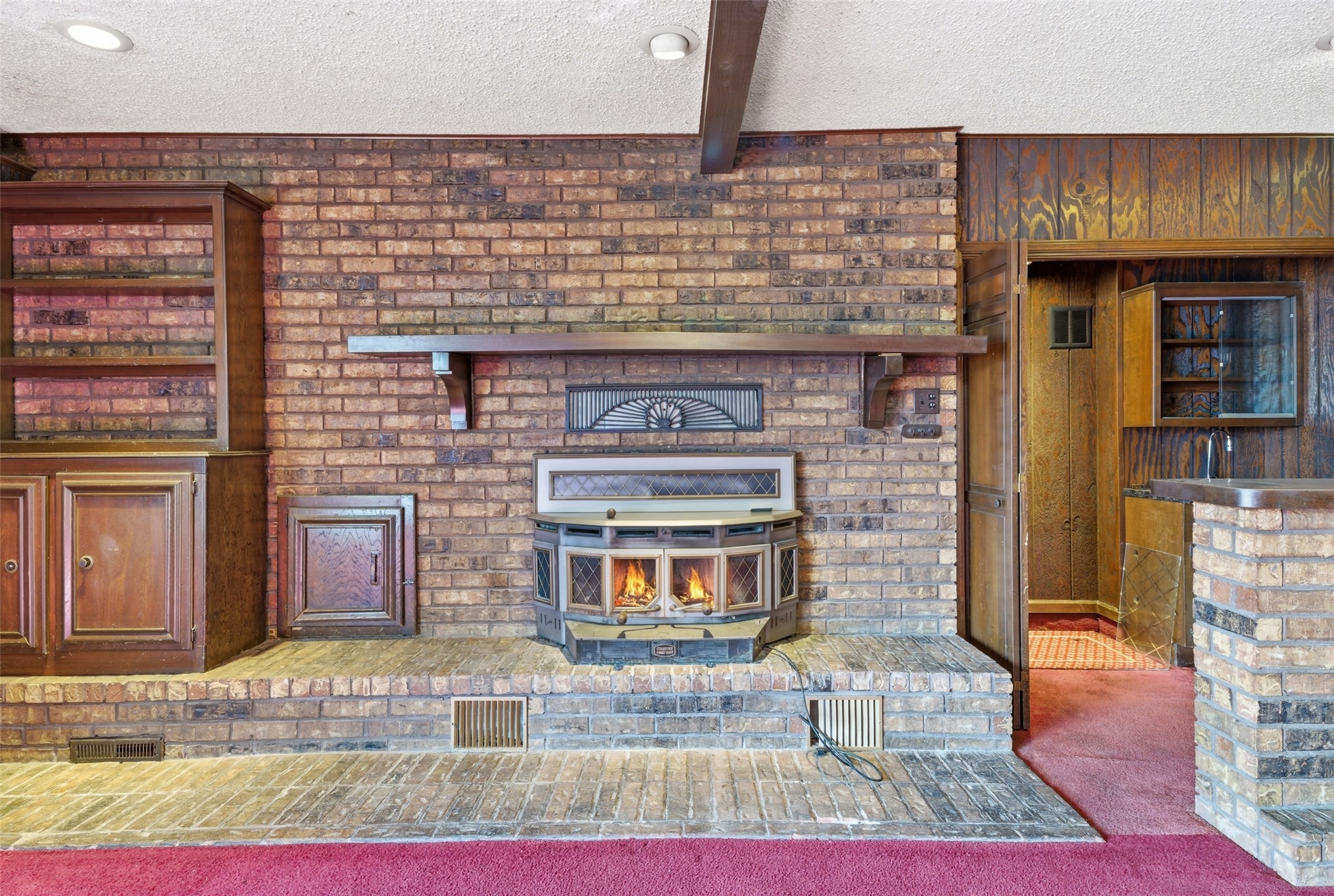 17875 East 589 Road Inola, OK 74036 - Photo 42 of 73 House #2 Brick accent wall featuring a central wood-burning stove, built-in cabinetry, and a wood mantle