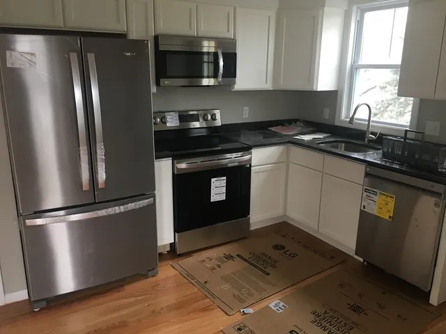 a kitchen with granite countertop a refrigerator sink and microwave