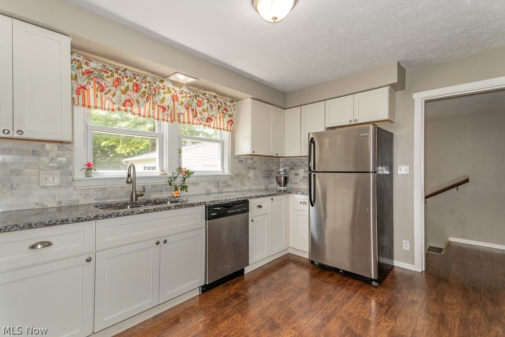 38488 Bell Road Willoughby, OH 44094 - Photo 3 of 22 Kitchen with stainless steel appliances, sink, backsplash, white cabinetry, and dark wood-type flooring