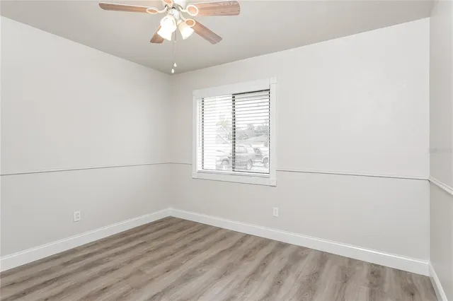 an empty room with wooden floor fan and windows